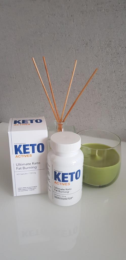 Keto Actives 16 white pill box and bottle with blue letters, along with a glass with green liquid and air freshener sticks.
