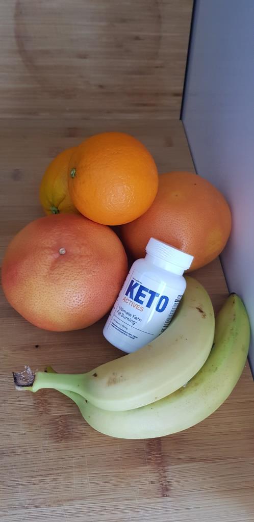 Keto Actives 17 white pill box and bottle with blue letters, on top of oranges and bananas.