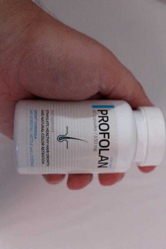 Profolan 2 hand holds a bottle of pills.