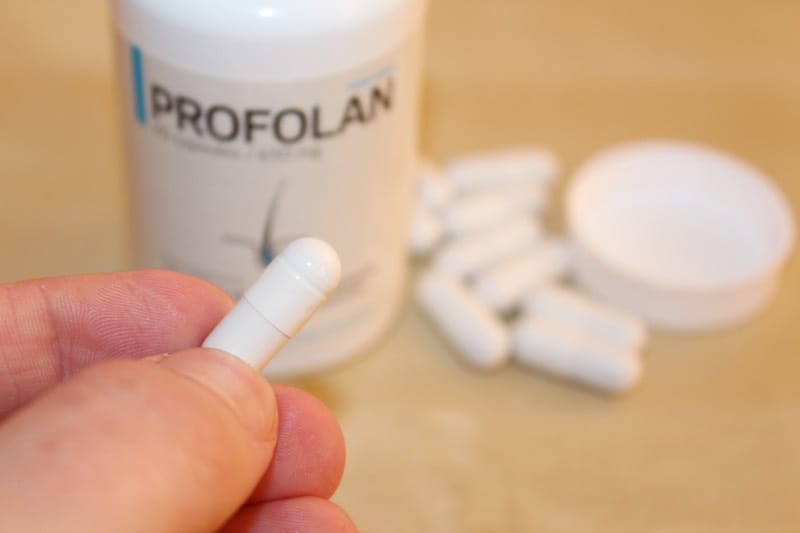 Profolan 11 hand holds a bottle of pills.