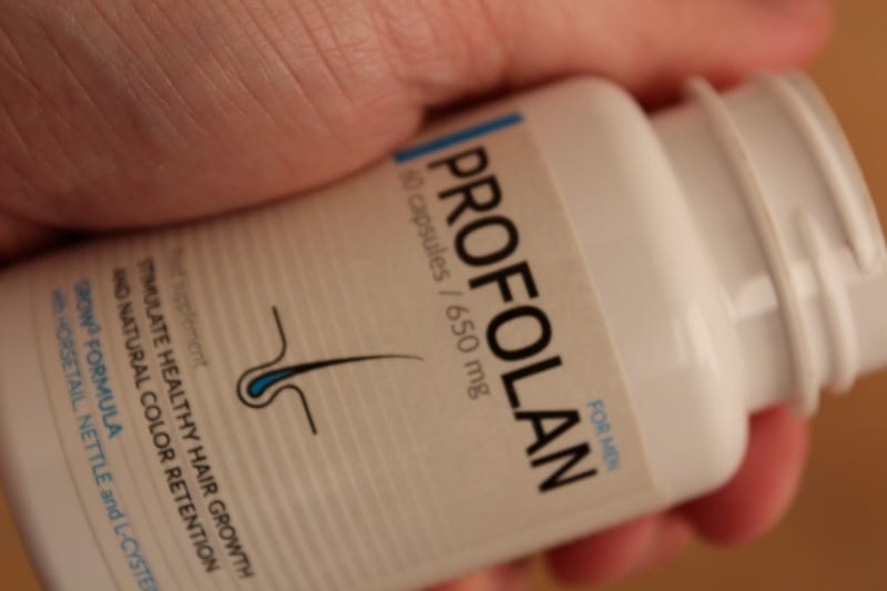 Profolan 12 hand holds a bottle of pills.